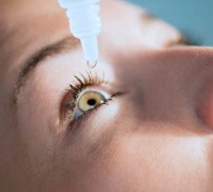 Showing a person apply an eye drop into their eye