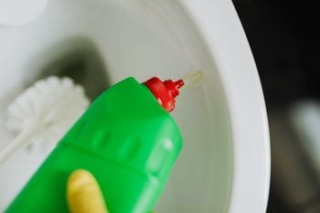 Person pouring liquid toilet cleaner in toilet bowl