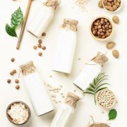 An image of milk bottles against a white background surrounded by various nuts.
